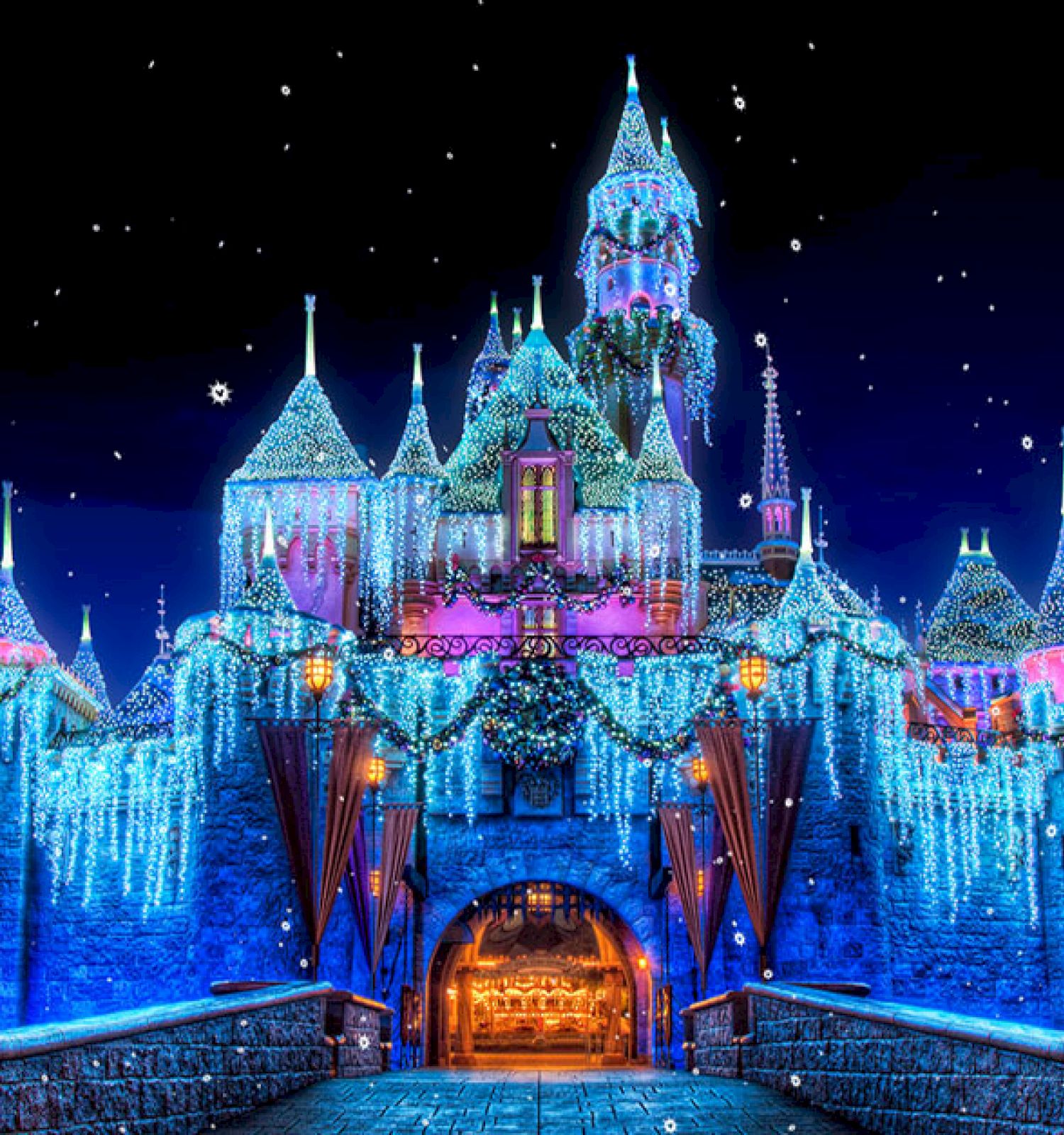 The image shows a brightly lit, snow-covered castle with icicle decorations against a night sky, creating a magical winter scene.